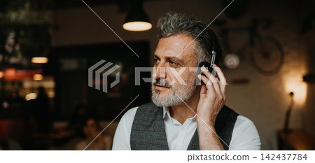 Mature worker having videocall, wearing headphones. Mature worker having videocall, wearing headphones. 142437784