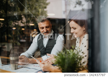 Woman showing project to client during business meeting in a coffee shop. Woman showing project to client during business meeting in a coffee shop. 142437787