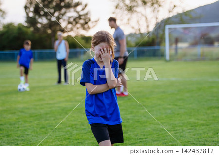 Disappointed young soccer player crying after difficult moment during football match. Disappointed young soccer player crying after difficult moment during football match. 142437812
