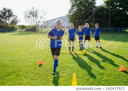 Young athletes training footwork and coordination on soccer field. Young athletes training footwork and coordination on soccer field. 142437821