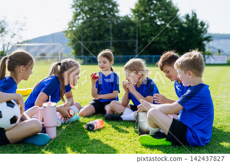Children relaxing together after youth football training and exercise. Children relaxing together after youth football training and exercise. 142437827