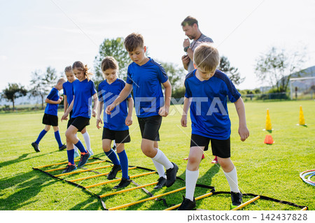 Young soccer players practicing agility ladder drills during training Young soccer players practicing agility ladder drills during training 142437828
