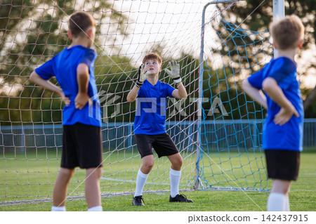 Young goalkeeper catching football during soccer play. Young goalkeeper catching football during soccer play. 142437915