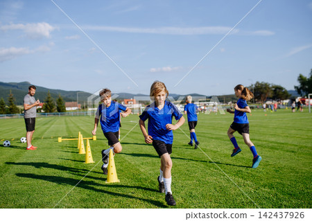 Young athletes training footwork and coordination on soccer field. Young athletes training footwork and coordination on soccer field. 142437926
