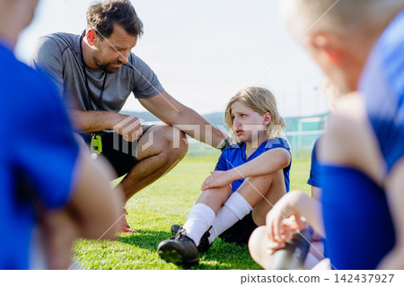Youth football team supporting injured teammate during training. Youth football team supporting injured teammate during training. 142437927