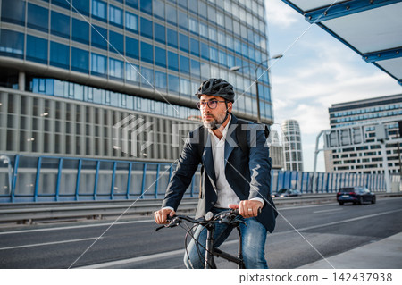 Businessman in front of office building, holding tablet and reading something. Businessman in front of office building, holding tablet and reading something. 142437938