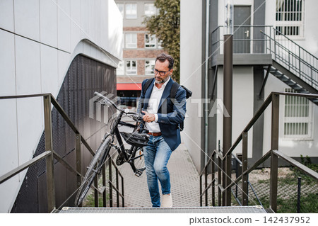 City commuter carrying bicycle up urban stairs. City commuter carrying bicycle up urban stairs. 142437952
