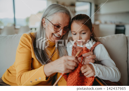 Grandmother teaching young girl how to knit, spending weekend with her. Grandmother teaching young girl how to knit, spending weekend with her. 142437985