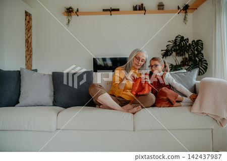 Grandmother teaching young girl how to knit, spending weekend with her. Grandmother teaching young girl how to knit, spending weekend with her. 142437987