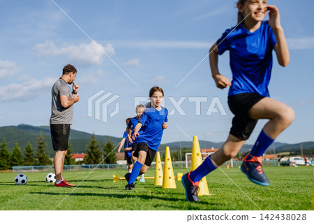 Young soccer players running aroung training cones during football practice Young soccer players running aroung training cones during football practice 142438028