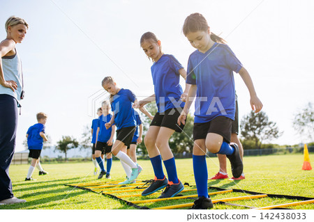 Young soccer players practicing agility ladder drills during training Young soccer players practicing agility ladder drills during training 142438033
