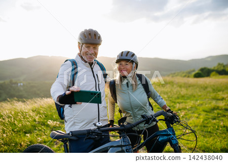 Senior couple taking selfie with smartphone during bike trip. Senior couple taking selfie with smartphone during bike trip. 142438040