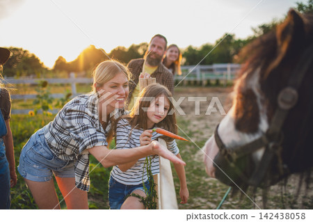 Mother and daughter feeding horse during family visit to countryside farm. Mother and daughter feeding horse during family visit to countryside farm. 142438058