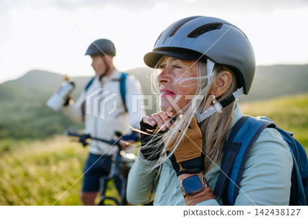 Active senior couple preparing for electric bike trip. Active senior couple preparing for electric bike trip. 142438127