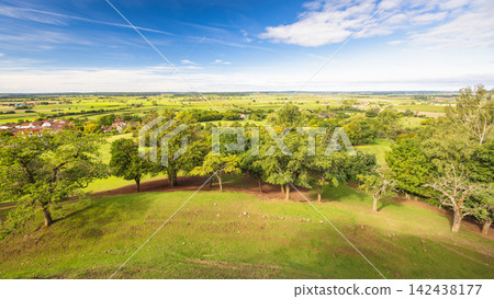 Panoramic rural landscape with rolling green hills, lush trees, distant village, and bright blue sky on a clear day. Region of Bavaria in Germany, Europe. Panoramic rural landscape with rolling green hills, lush trees, distant village, and bright blue sky on a clear day. Region of Bavaria in Germany, Europe. 142438177