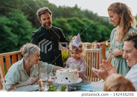 Multi generation family grilling outside on patio in summer during garden party Multi generation family grilling outside on patio in summer during garden party 142438208