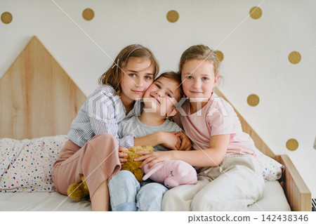Three sisters sharing a loving hug in their bedroom. Three sisters sharing a loving hug in their bedroom. 142438346