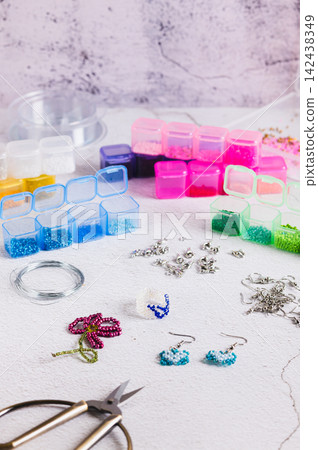 A set for weaving jewelry from colorful beads on a worktable vertical view A set for weaving jewelry from colorful beads on a worktable vertical view 142438349