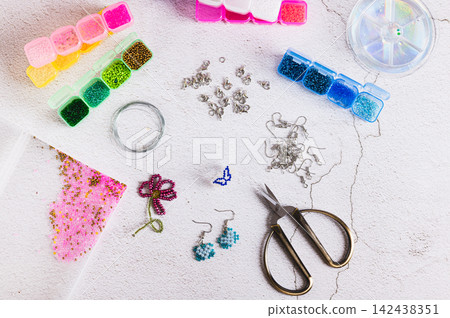 A set for weaving jewelry from colorful beads on a worktable top view A set for weaving jewelry from colorful beads on a worktable top view 142438351