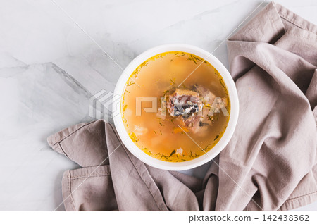 Close up of simple budget soup with canned sardines and vegetables in a bowl on the table top view Close up of simple budget soup with canned sardines and vegetables in a bowl on the table top view 142438362
