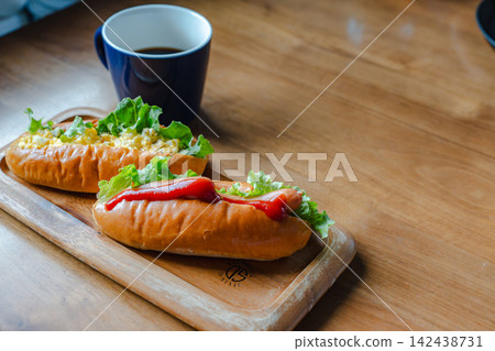 一份熱狗,配上雞蛋沙拉和香腸,放在木托盤上,再配上一杯咖啡。 一份熱狗,配上雞蛋沙拉和香腸,放在木托盤上,再配上一杯咖啡。 142438731