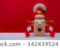 A photograph showing a real red and white rice cake ("kagami mochi") placed on the right, against a red and white background, with a sanbo (stand) attached. 142439524
