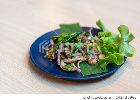 Thai spicy liver salad mixed onion chili mint fresh herbs served green lettuce blue plate for flavorful traditional meal Thai spicy liver salad mixed onion chili mint fresh herbs served green lettuce blue plate for flavorful traditional meal 142439962