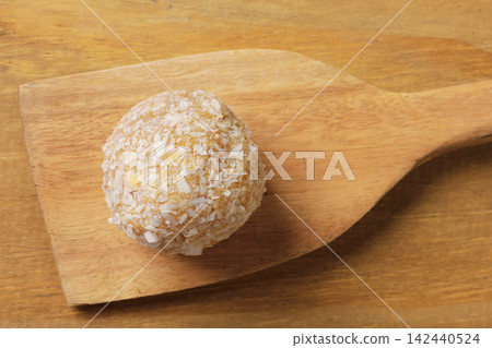 Brazilian coconut beijinho on a wooden spatula on a rustic wooden table. Traditional confectionery for parties and celebrations Brazilian coconut beijinho on a wooden spatula on a rustic wooden table. Traditional confectionery for parties and celebrations 142440524