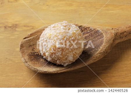 Brazilian coconut beijinho on a wooden spoon on a rustic wooden table. Traditional confectionery for parties and celebrations. 142440526