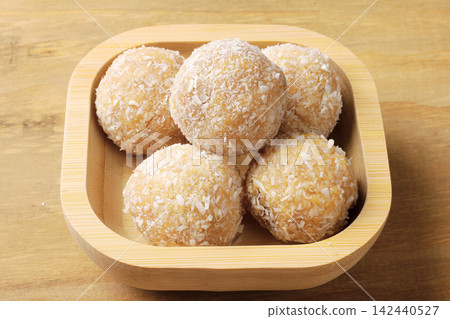 Traditional Brazilian beijinho coated in shredded coconut, served in a bamboo bowl. A dessert for parties and birthdays. Traditional Brazilian beijinho coated in shredded coconut, served in a bamboo bowl. A dessert for parties and birthdays. 142440527