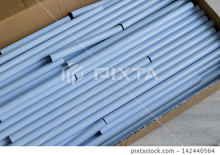 Cardboard Box Filled with Light Blue Plastic Tubes 142440564