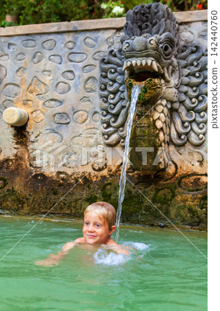 Little child swimming in thermal pool, relax under flowing water stream of shower in natural mineral hot spring Banjar. Day tour on family holidays with kids. Popular travel destination in north Bali Little child swimming in thermal pool, relax under flowing water stream of shower in natural mineral hot spring Banjar. Day tour on family holidays with kids. Popular travel destination in north Bali 142440760