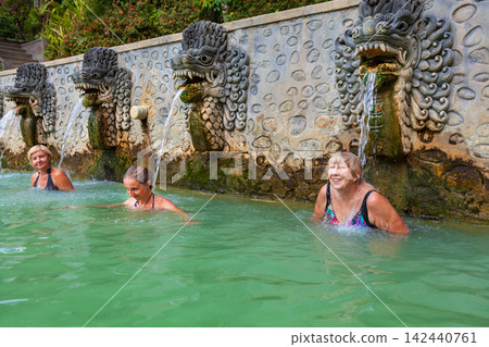 3 generations of women in thermal bath, relaxing under flowing water stream of shower in natural mineral hot spring Air Panas Banjar. Family day tour on vacation. Popular travel destination in Bali 3 generations of women in thermal bath, relaxing under flowing water stream of shower in natural mineral hot spring Air Panas Banjar. Family day tour on vacation. Popular travel destination in Bali 142440761