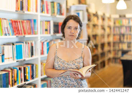 In bookstore woman choose book In bookstore woman choose book 142441247
