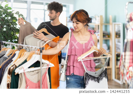 Young couple choosing dress and t-shirt in clothing store Young couple choosing dress and t-shirt in clothing store 142441255