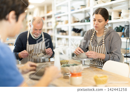 Young woman and man and elderly man crafting ceramics Young woman and man and elderly man crafting ceramics 142441258