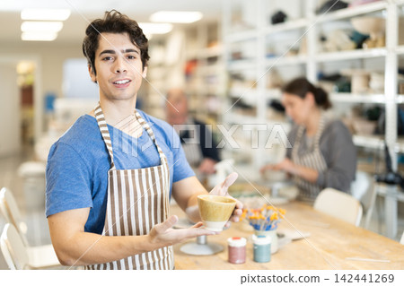 Young man holding finished ceramic piece Young man holding finished ceramic piece 142441269