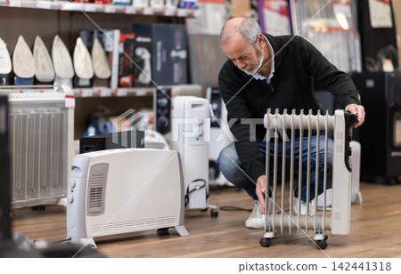 Elderly man choosing oil heater in store Elderly man choosing oil heater in store 142441318