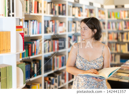 Adult woman choosing book in bookstore Adult woman choosing book in bookstore 142441357