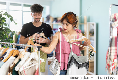Guy helping girlfriend choose summer summer at store Guy helping girlfriend choose summer summer at store 142441390