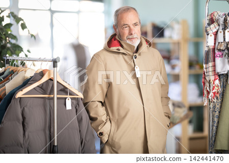 Elderly man trying on brown jacket in store Elderly man trying on brown jacket in store 142441470