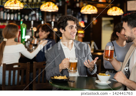 Young men sitting in bar drinking beer Young men sitting in bar drinking beer 142441763
