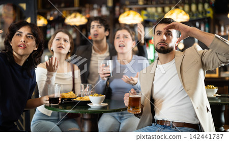 Group of friends watching sports match in disappointment Group of friends watching sports match in disappointment 142441787
