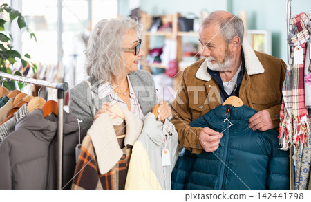 Elderly couple choosing jackets and coats together Elderly couple choosing jackets and coats together 142441798