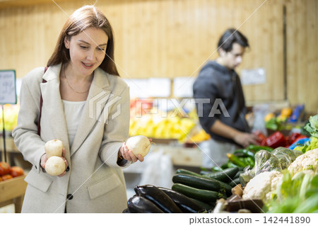 Girl shopping, examine vegetable in store and buy elect daikon radish Girl shopping, examine vegetable in store and buy elect daikon radish 142441890