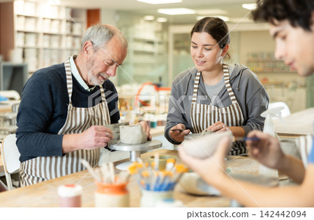 Young woman and man and elderly man crafting ceramics Young woman and man and elderly man crafting ceramics 142442094