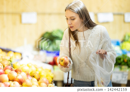 Young woman choosing apples in vegetable shop Young woman choosing apples in vegetable shop 142442159