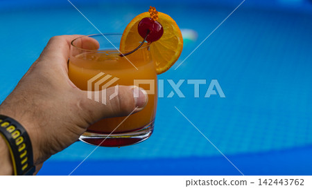 Enjoying a refreshing orange cocktail by the pool on a sunny day Enjoying a refreshing orange cocktail by the pool on a sunny day 142443762