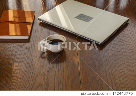 Morning work setup with coffee and laptop on wooden desk Morning work setup with coffee and laptop on wooden desk 142443770
