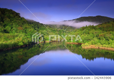 A lake surrounded by fresh greenery A lake surrounded by fresh greenery 142443906